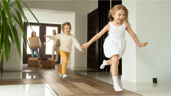 Excited children running into big modern house with parents in the background (small image)