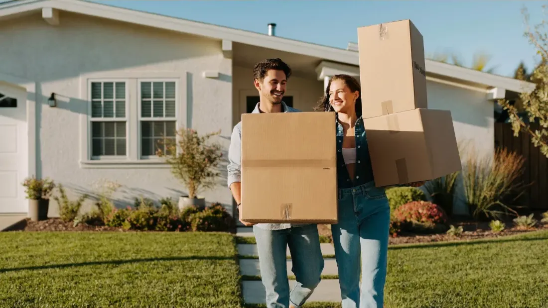 Compradores primerizos llevando cajas de mudanza a su nueva casa